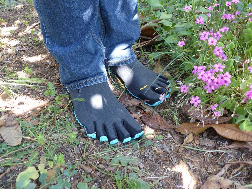 Photo vu de face des chaussures minimalistes Vibram fivefingers portées pieds-nus avec un jeans.